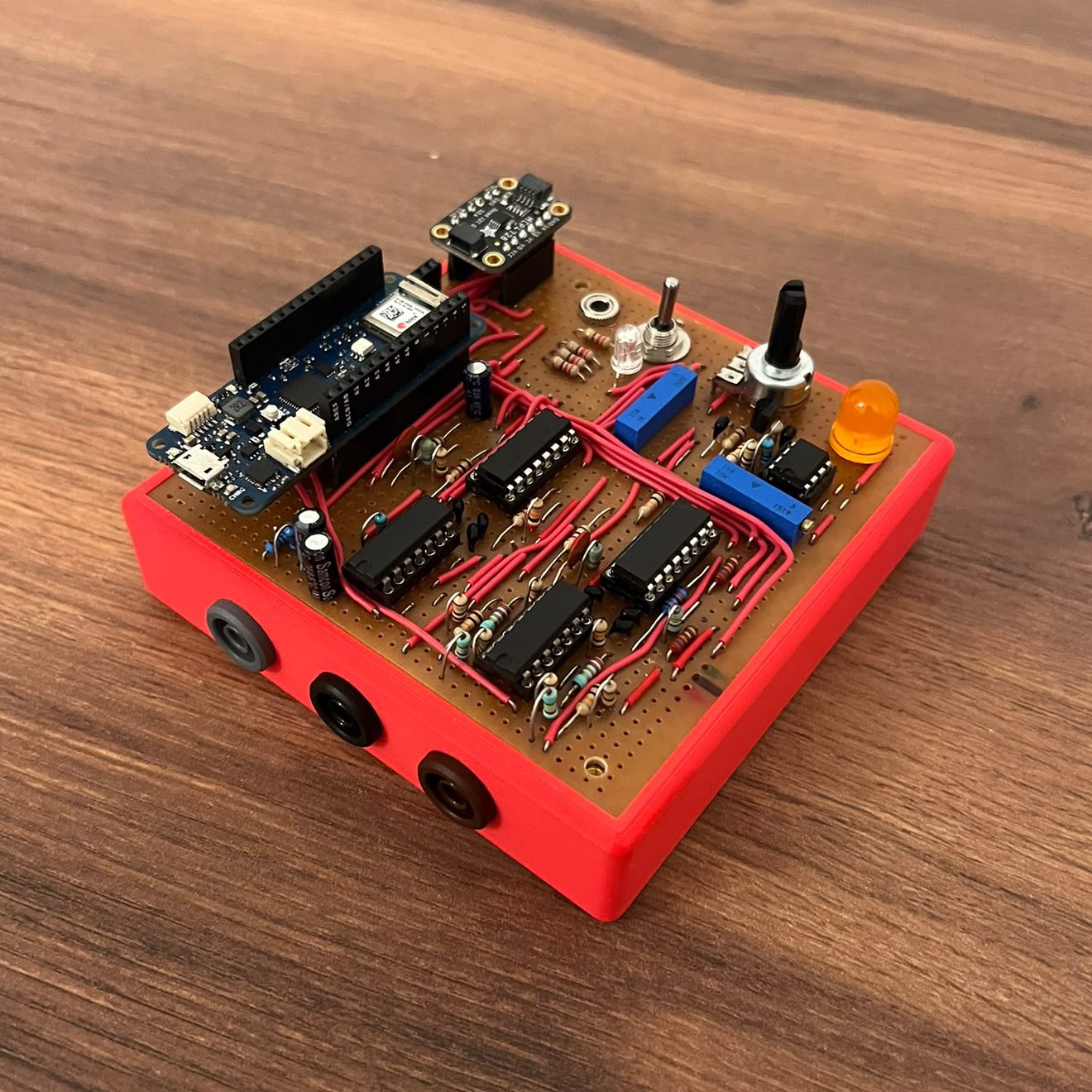 The synth: Arduino MKR WiFi 1010 and stripboard circuit in a red 3D-printed enclosure